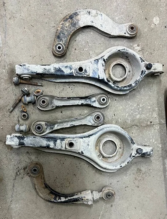 Снятые задние рычаги Ford Focus 2: два верхних серпа, два подпружинных с чашкой пружины, две косточки и регулировочные болты